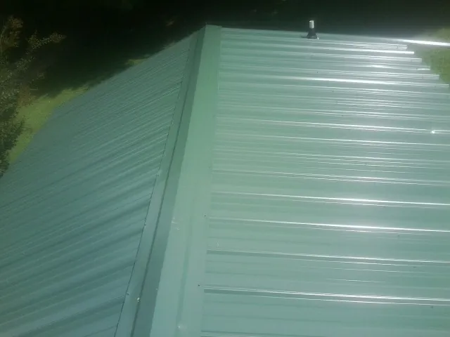 New green metal panels meeting at the ridge of a roof — Flat Roof Repair work by our crew in Crater Lake