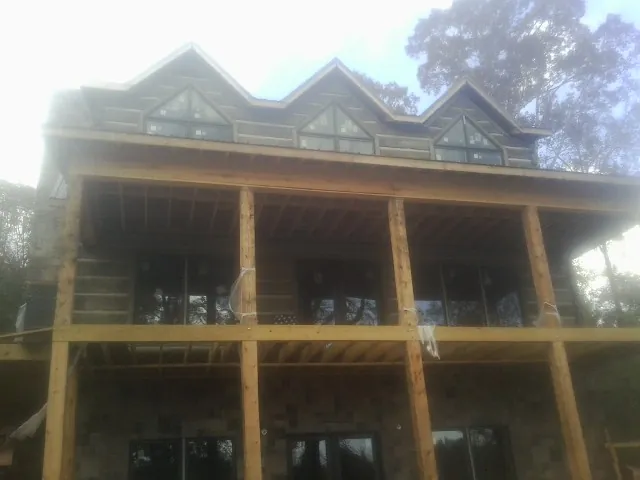 Dormers and porch framing on a large log home under construction — Roof Coating work by our crew in Crater Lake