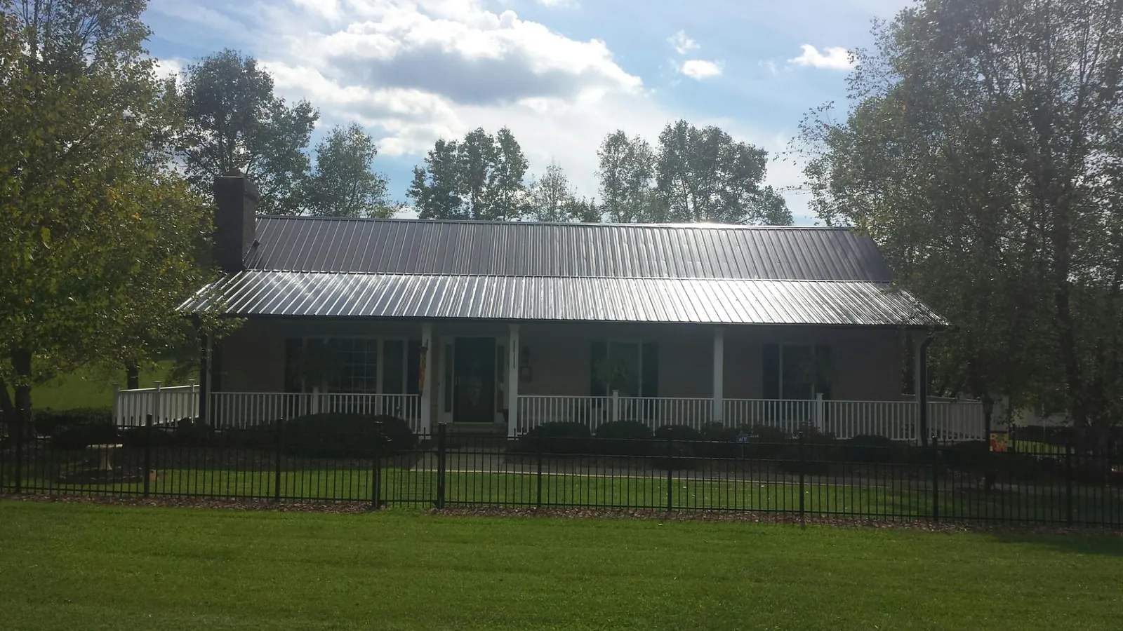 Gray metal roof on a brick ranch with a full width front porch — Gutter Guard Installation work by our crew in Crater Lake