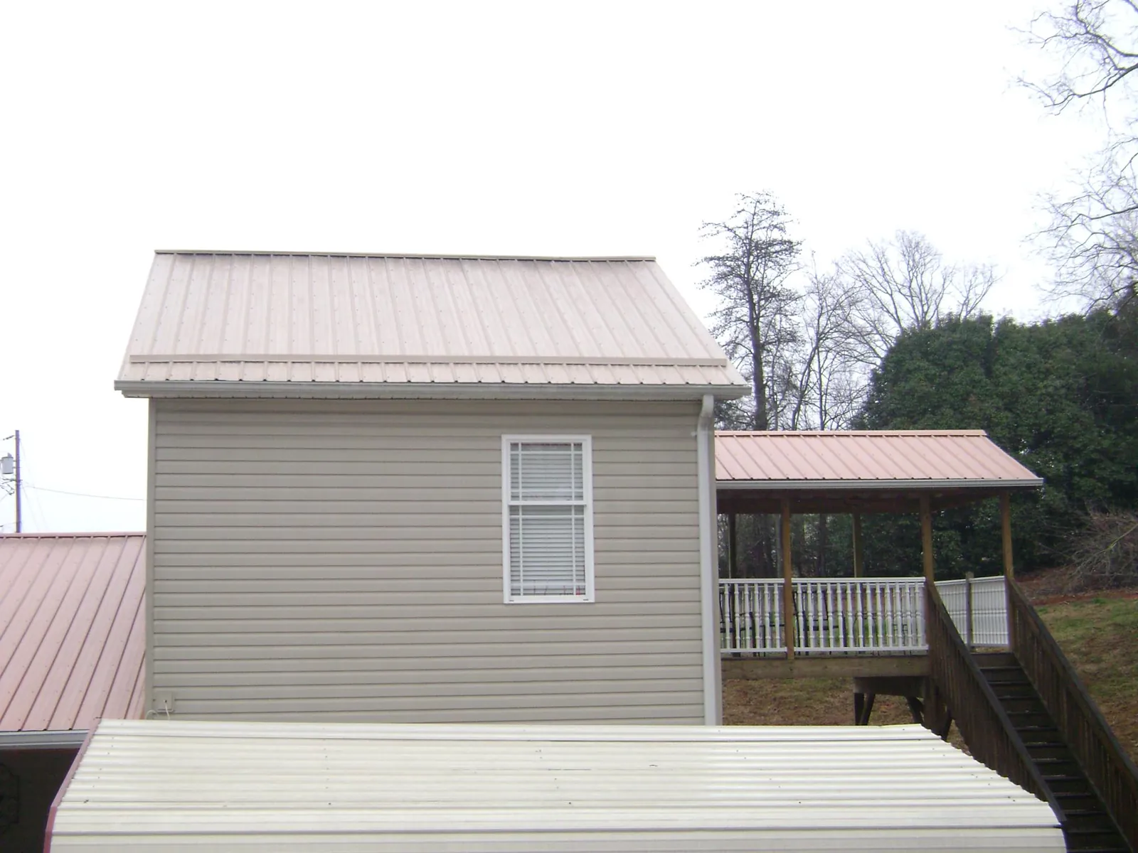 Tan metal roofs on a two story addition and attached porch, from a Roof Replacement job in Crater Lake