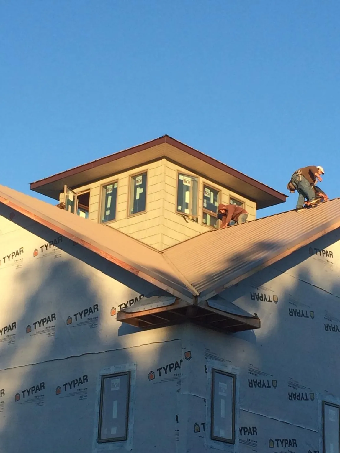 Roofers working around a rooftop cupola on a new metal roof at sunset — Roof Waterproofing in Crater Lake by Roofing Brothers